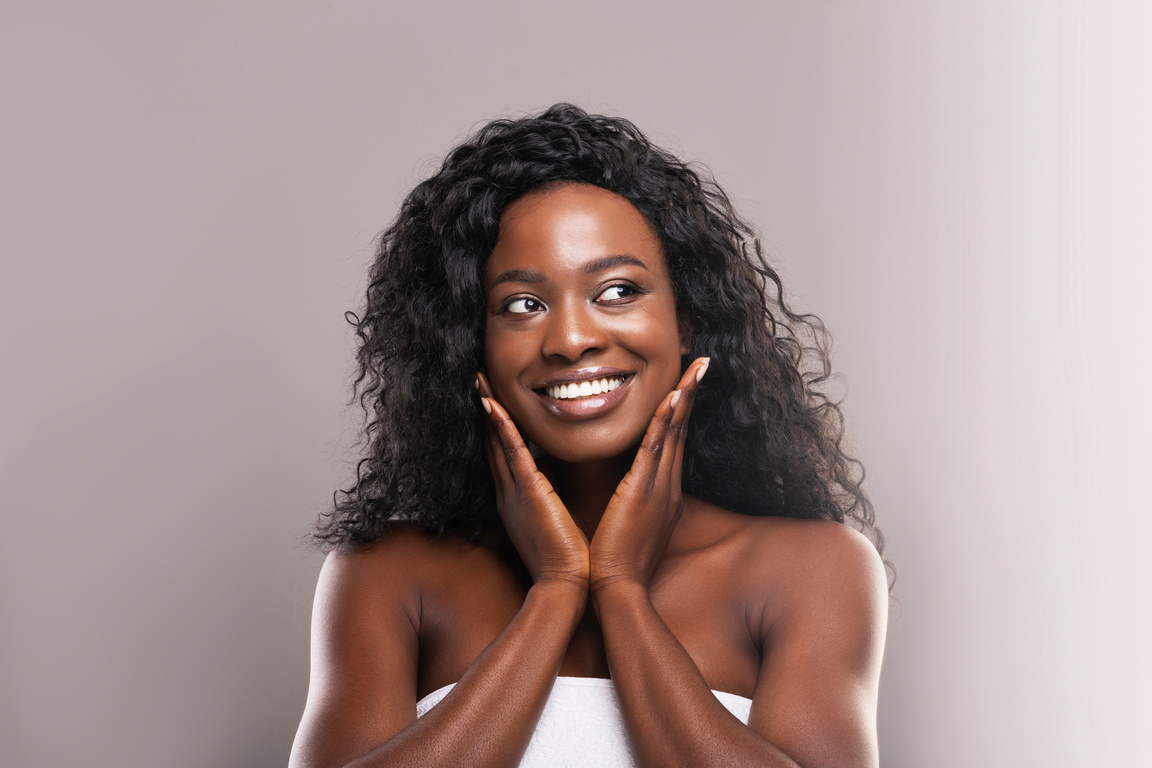 Beautiful black woman happy about her flawless skin on cheeks